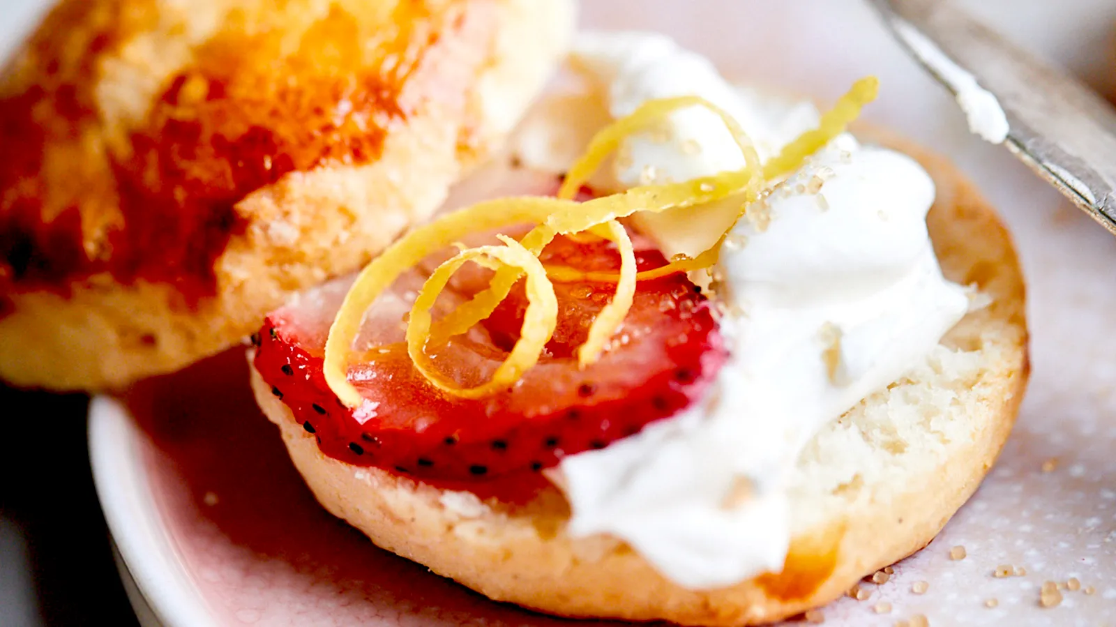 Scones cut in half with cream and strawberries