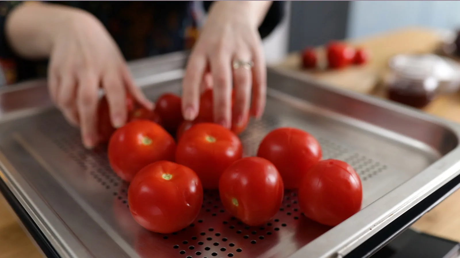 Person arranging tomatoes on baking tray