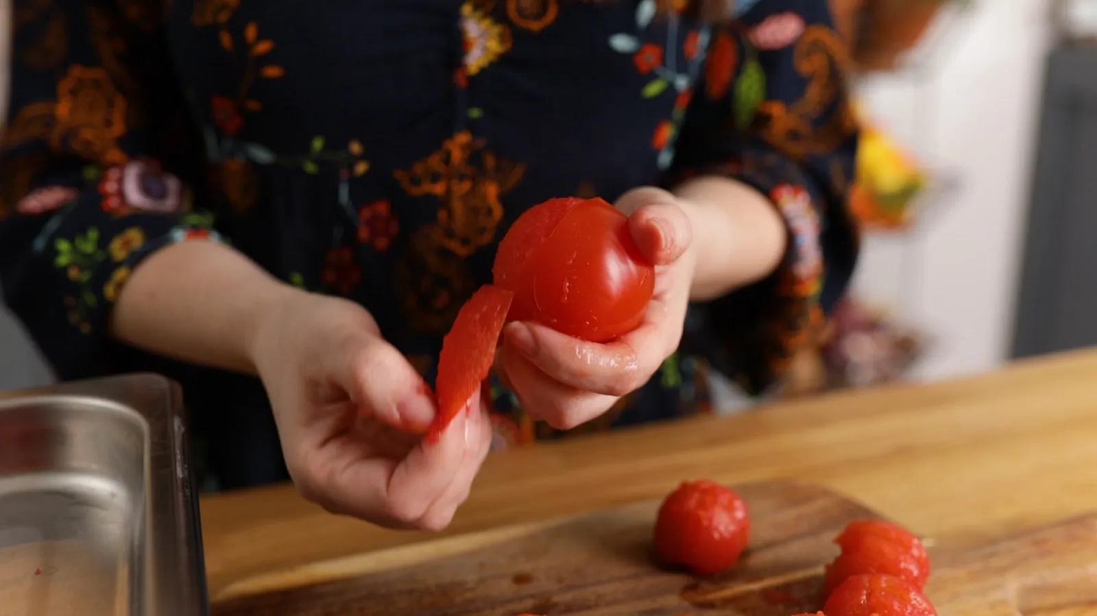 Person peeling skin from cooked tomatoes