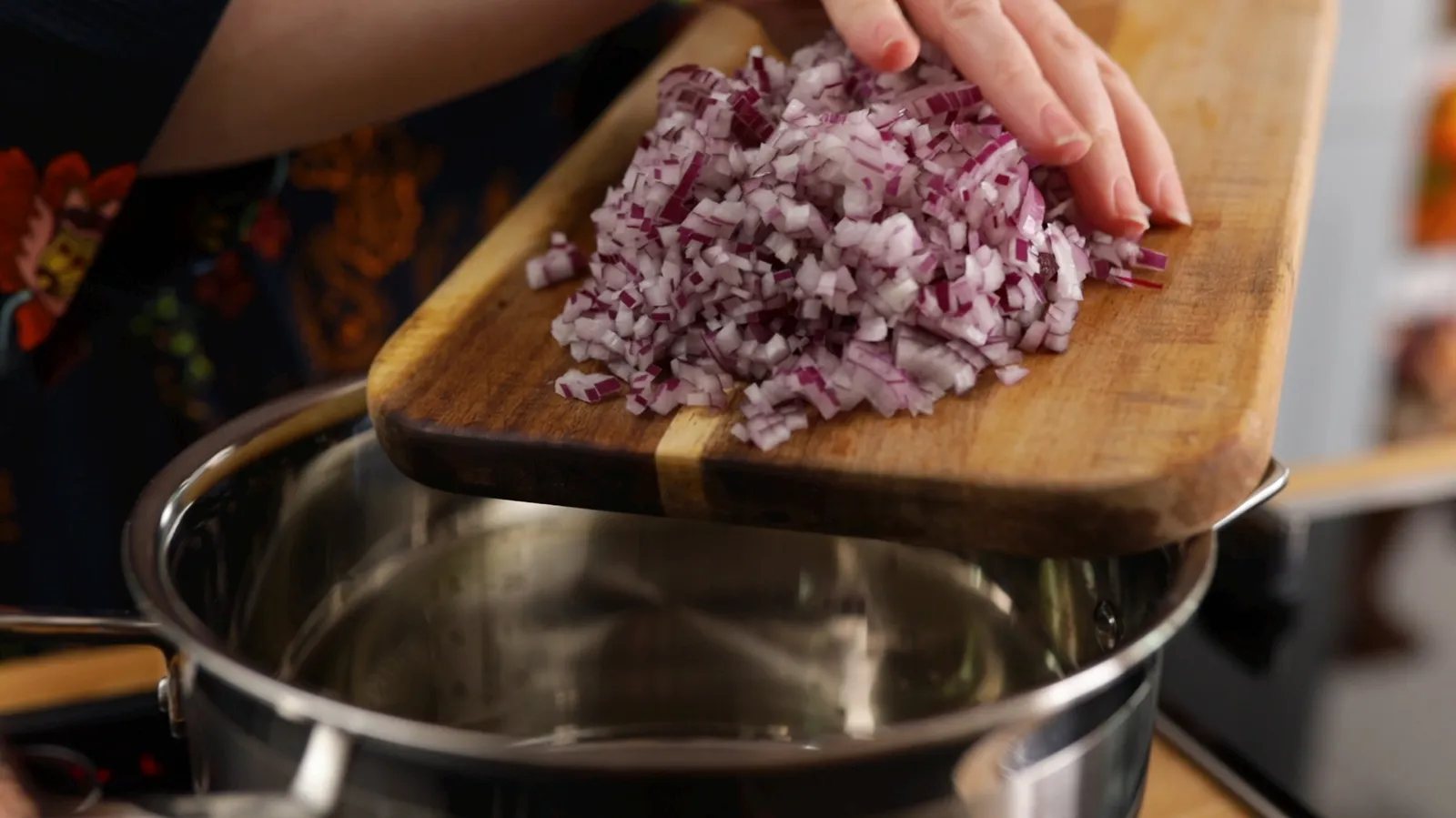 Person putting cooked onion into pan