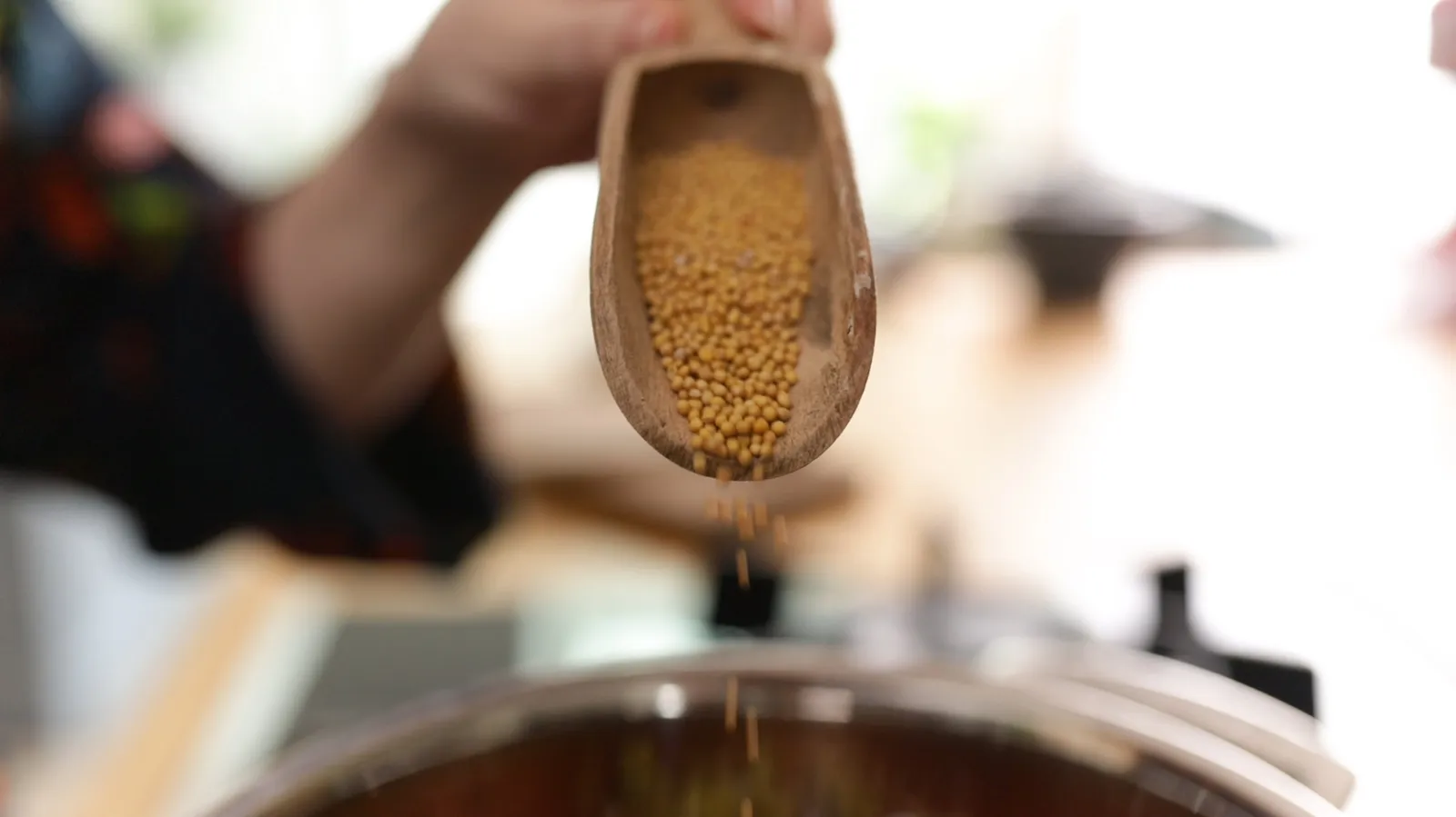 Pouring mustard seeds into pan