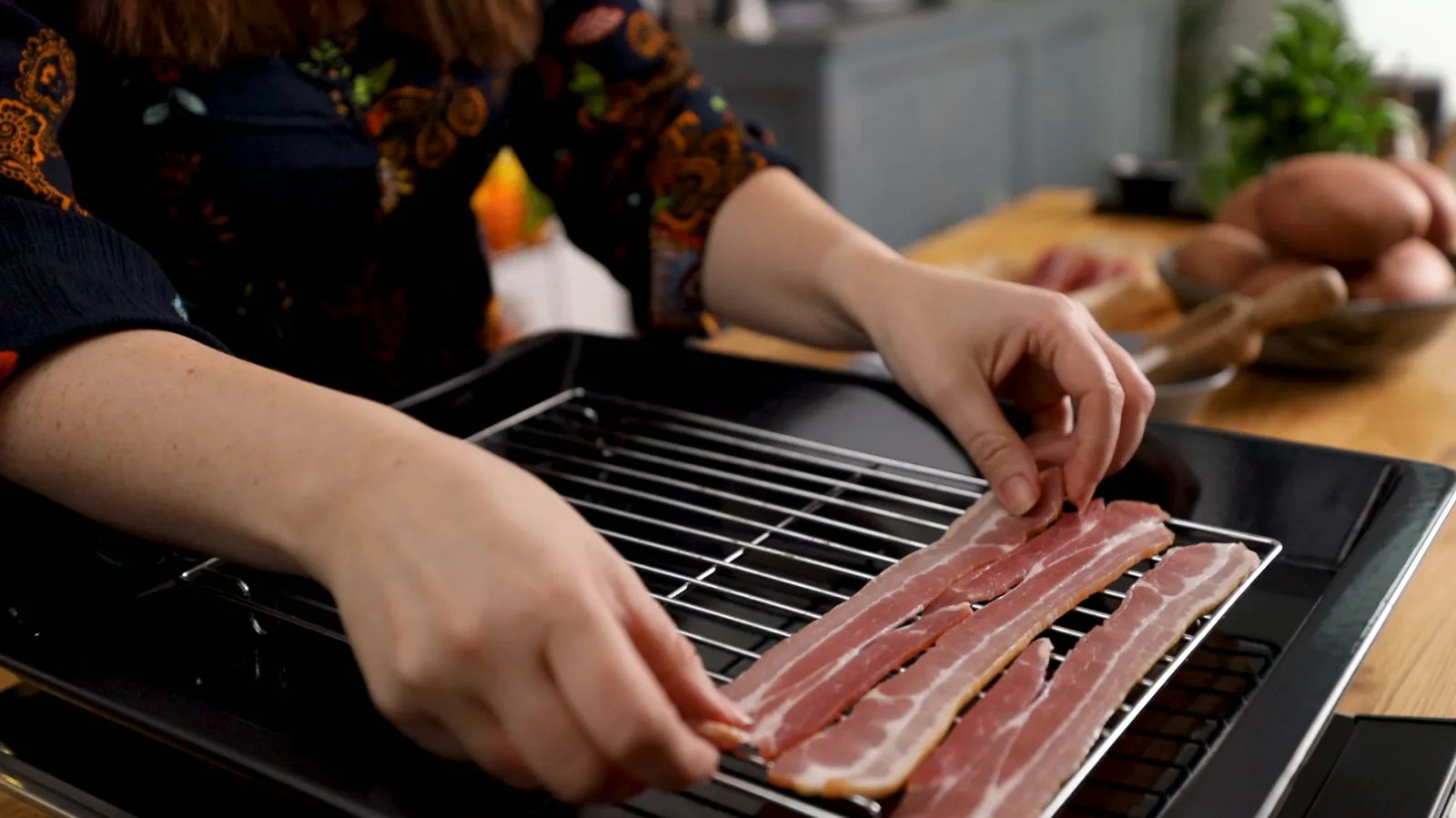 Person laying bacon on cooking tray