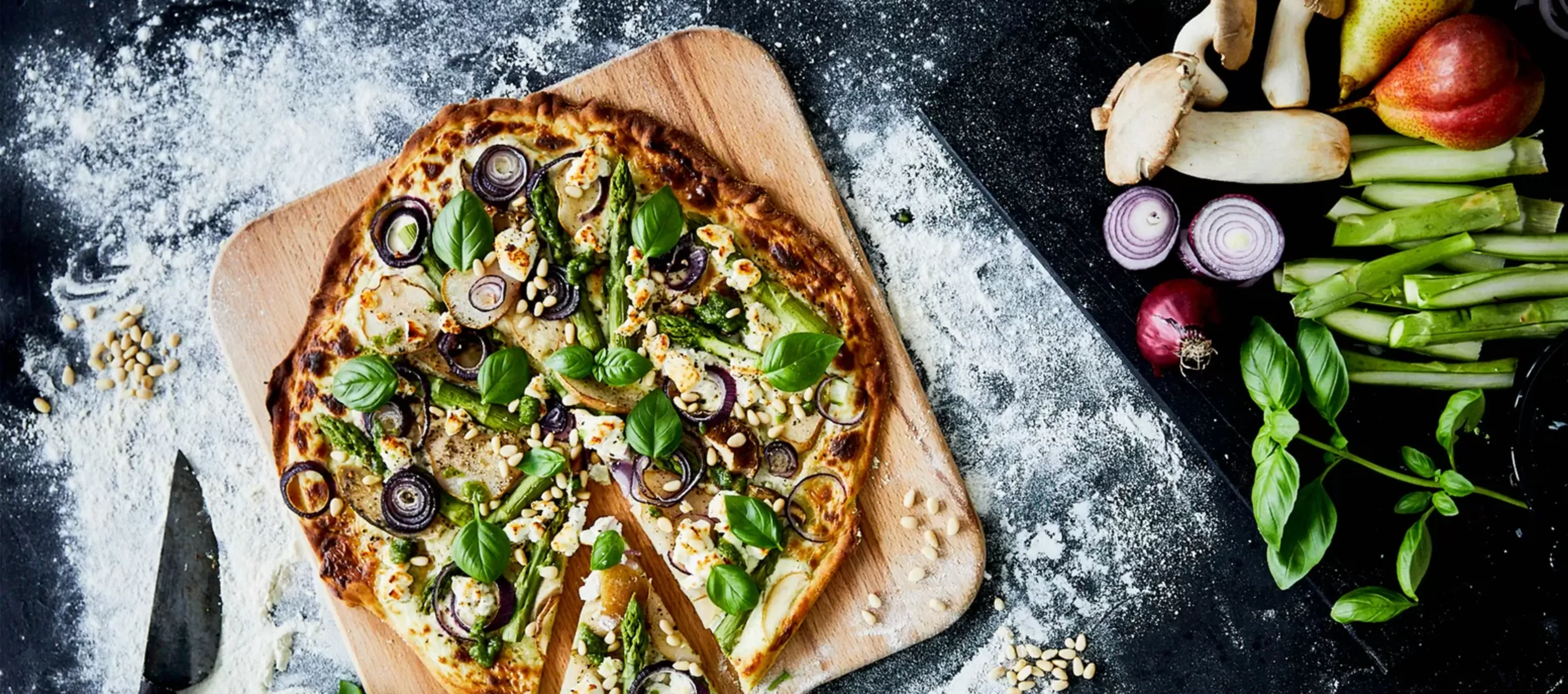 Homemade quiche with vegetables, mushrooms, and herbs on a wooden board surrounded by fresh produce.