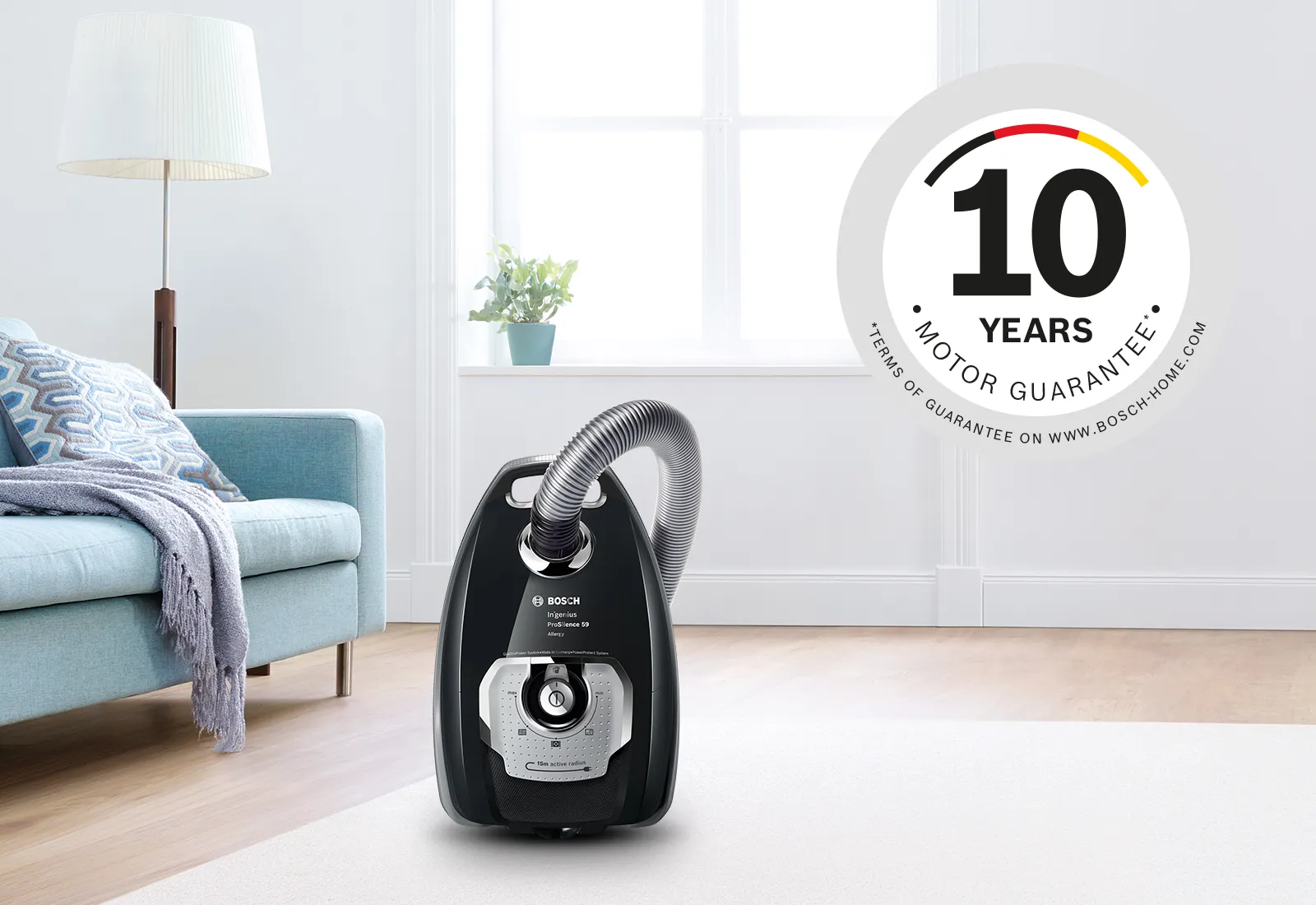 Black canister vacuum on a living room rug with a "10 years motor guarantee" badge.