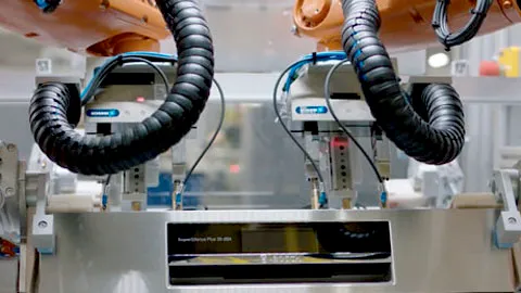 Industrial robotic arms assembling components in a factory setting.