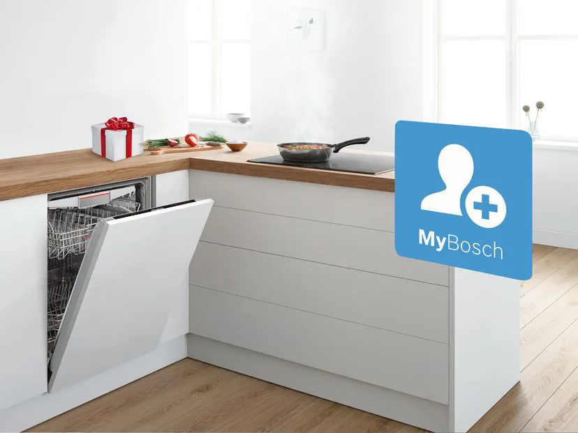 Lavastoviglie da incasso aperta in una moderna cucina bianca con piano di lavoro in legno. Gestisci la lavastoviglie con l'account MyBosch (icona blu).