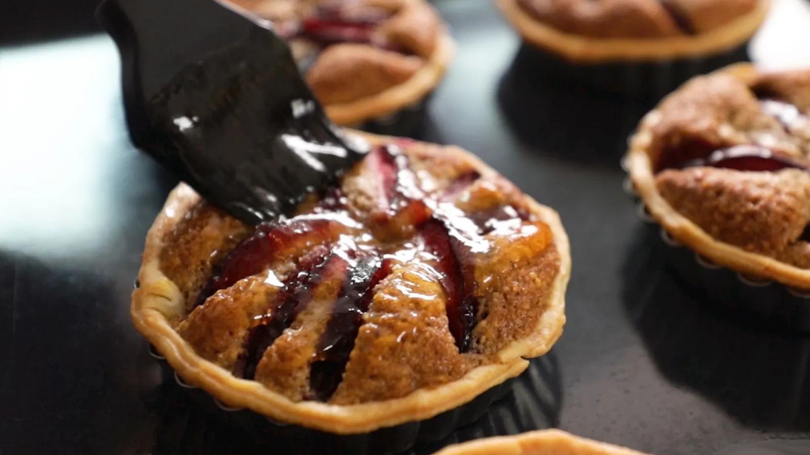 Apricot jam being spread over top of cooked tart