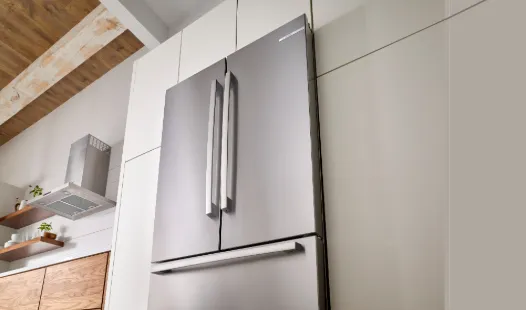 Bosch Stainless steel fridge with double doors and bottom freezer in a modern kitchen setting.