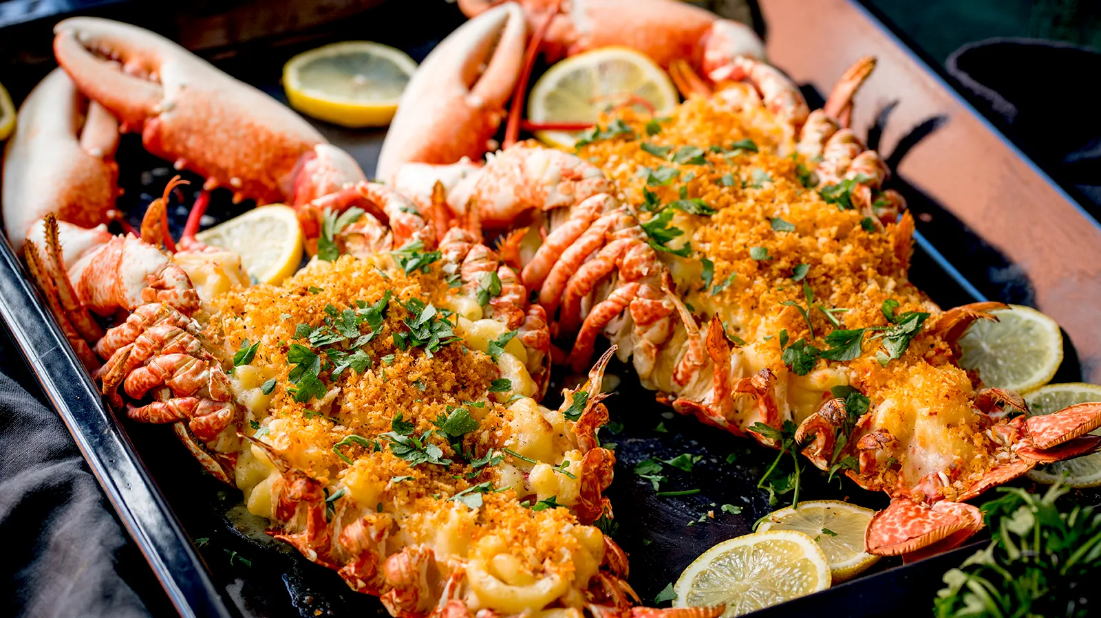 Seafood platter with lobster, crab, and lemon garnish on a dark background.