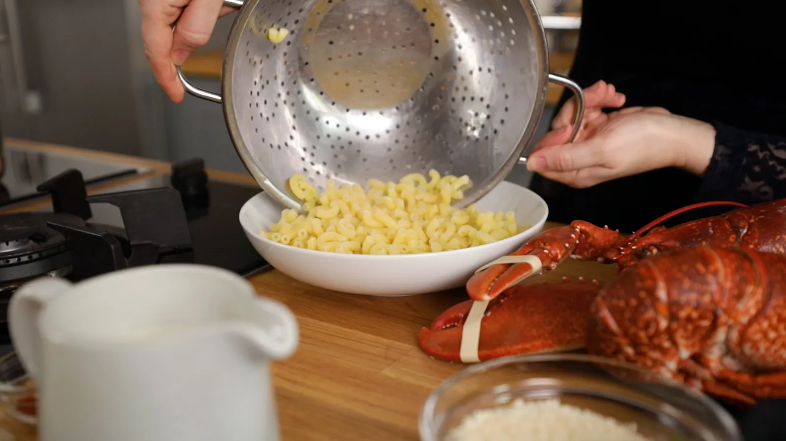 Cooking pasta, lobster, and other ingredients on a wooden table.