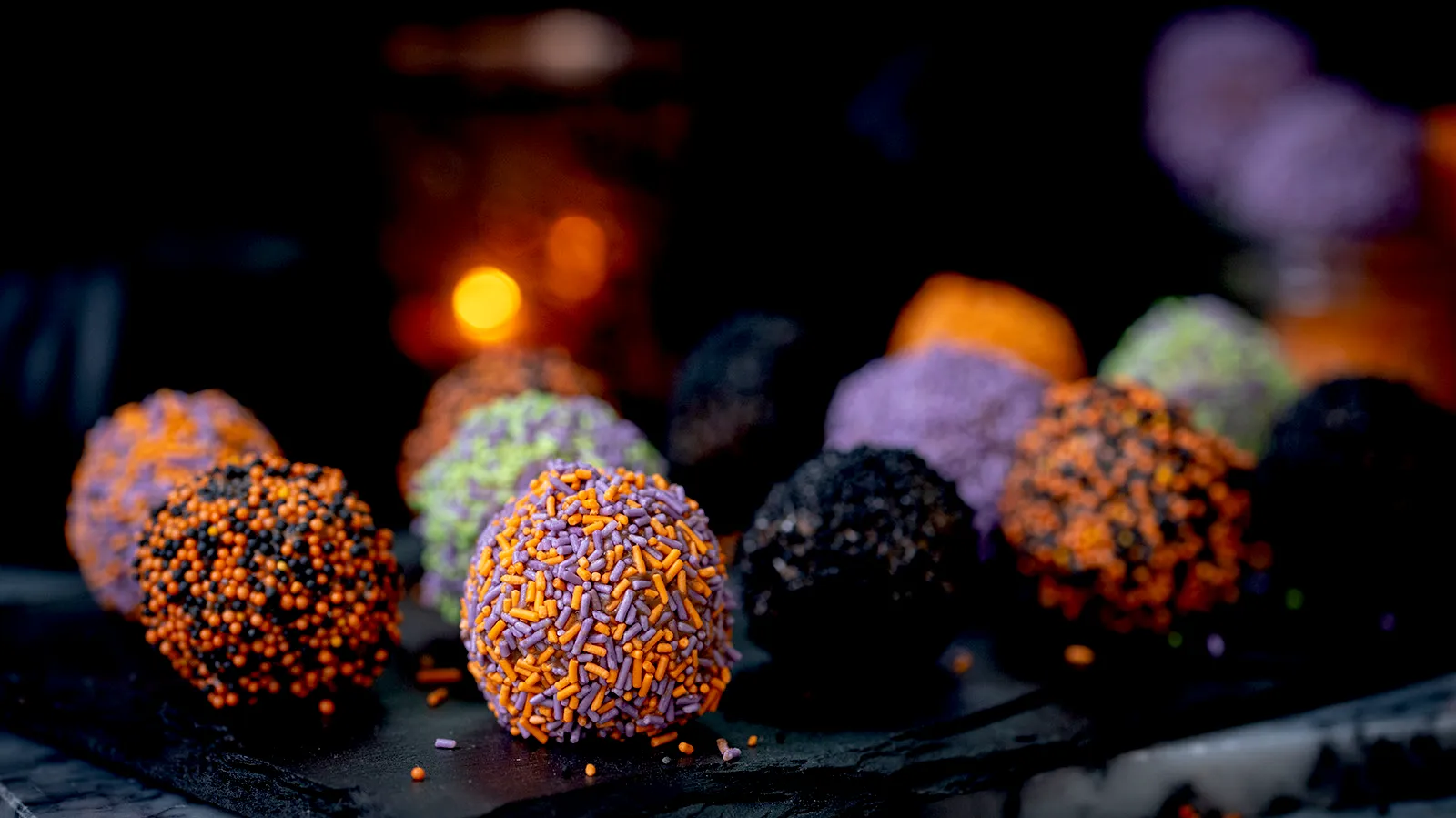 Colorful, textured truffles against a dark background with blurred lights.