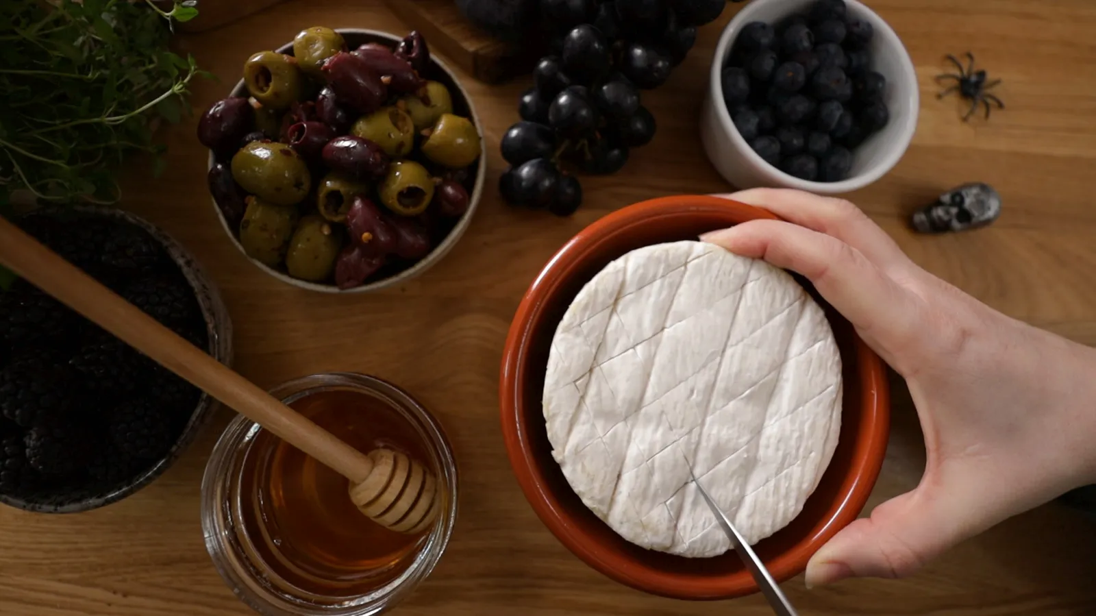 Person scoring the top of camembert with a knife