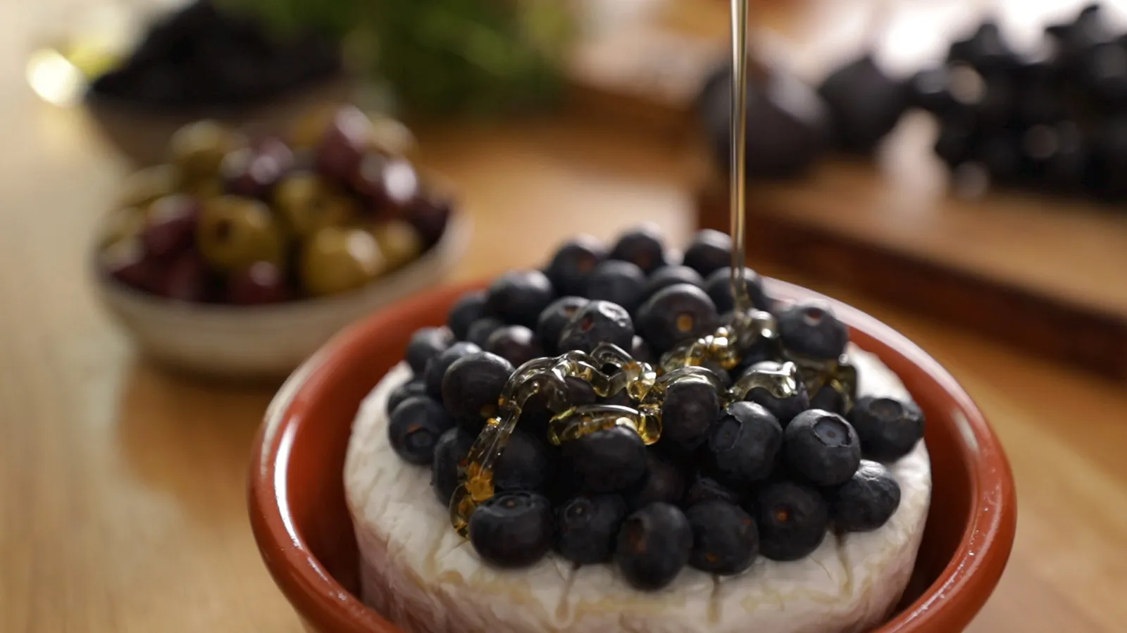 Drizzling honey over blueberries and camembert