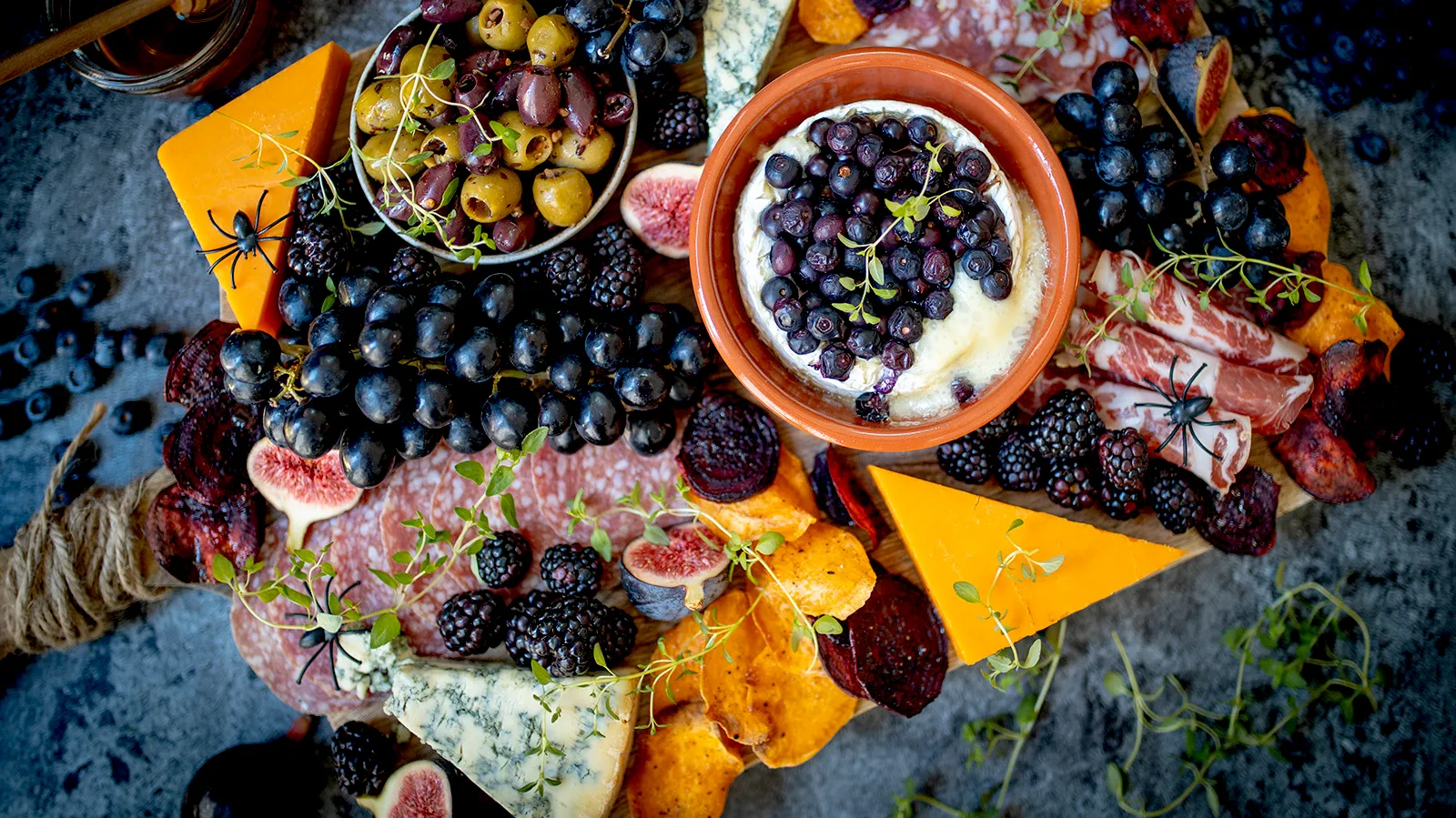 Assorted fresh fruits, berries, and cheese on a rustic wooden surface.
