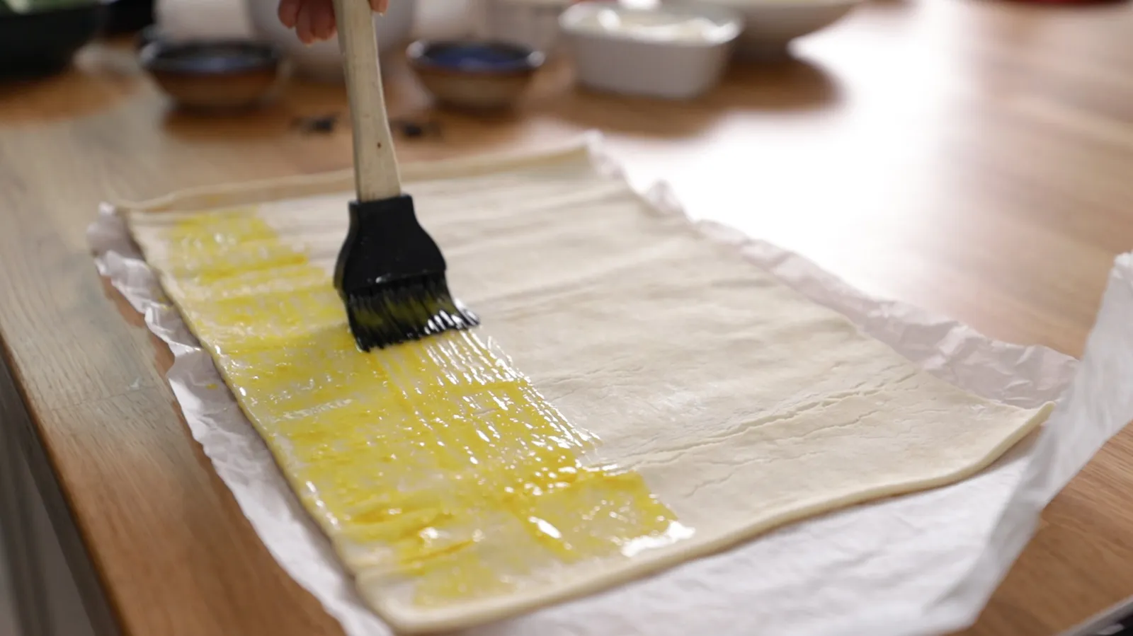 Person brushing pastry sticks with egg wash