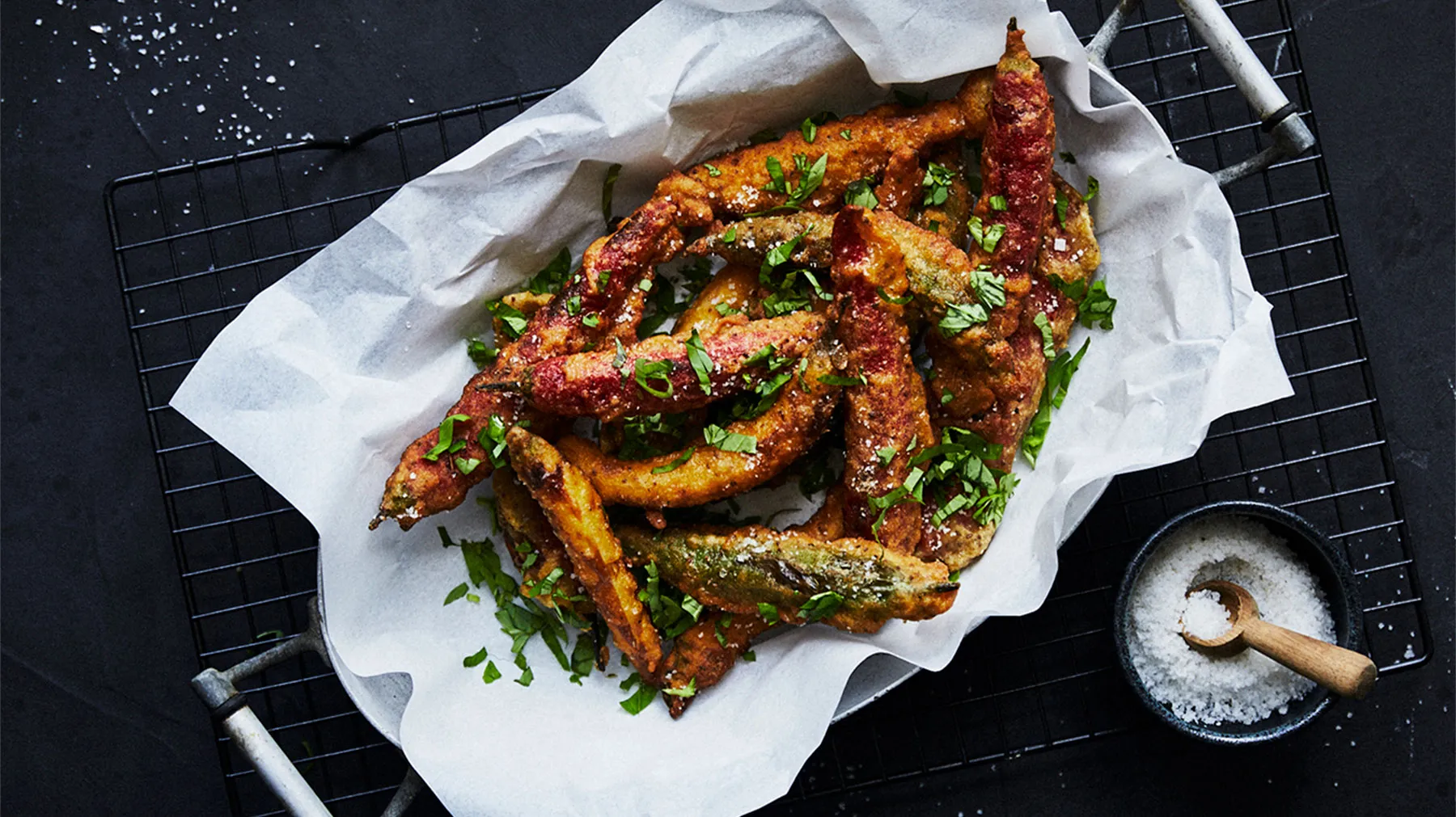 Crispy fried chicken wings with spicy sauce, garnished with green onions on a dark background.
