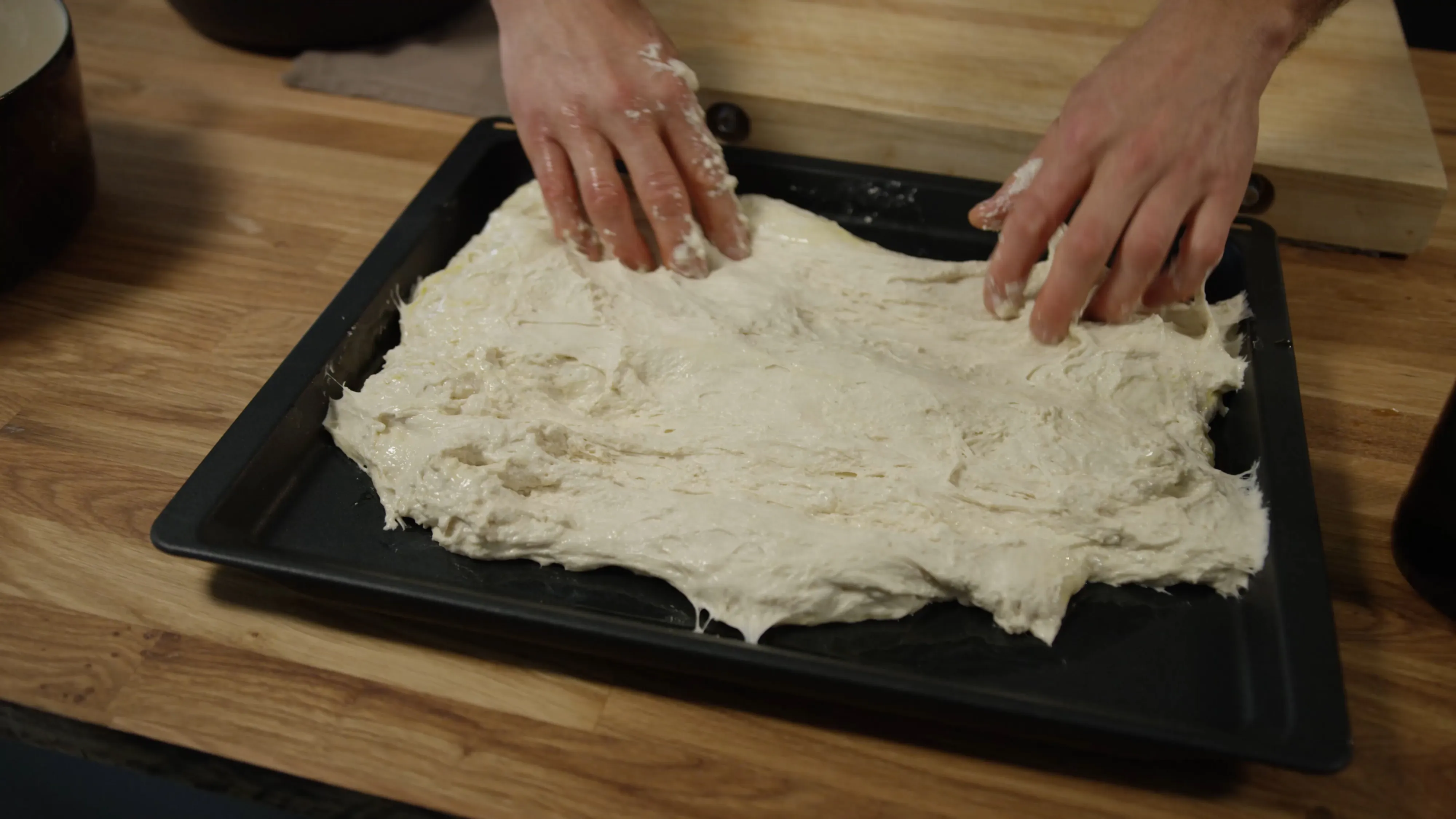 Focacciadeig formes med hendene på en benkeplate