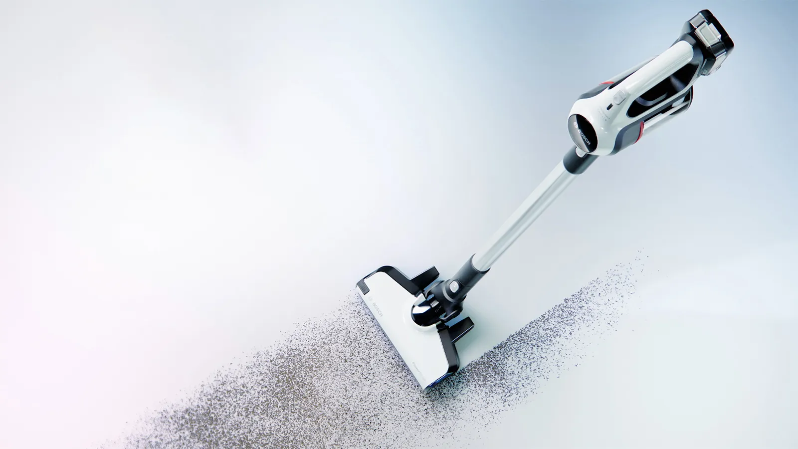 A white and black stick vacuum cleaner cleaning a path through dirt on a light floor.