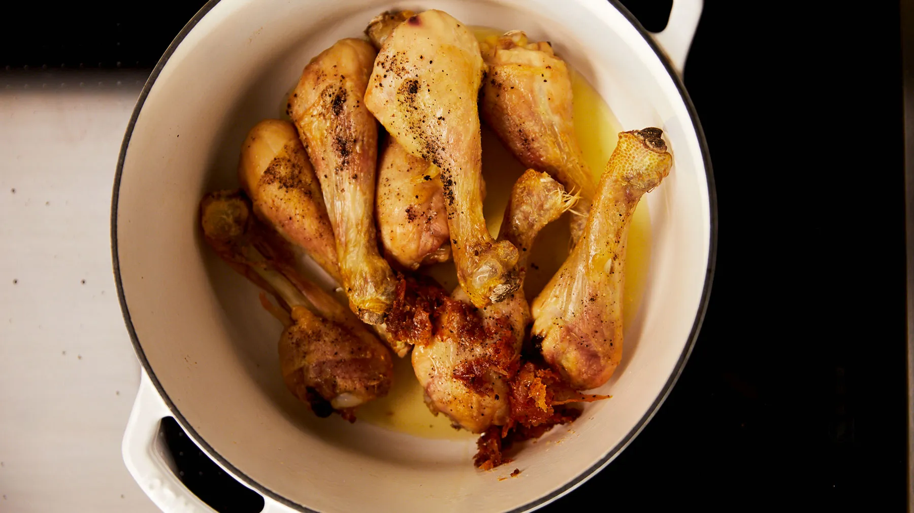 Roasted chicken drumsticks and thighs in a white dish, seasoned with spices and herbs.