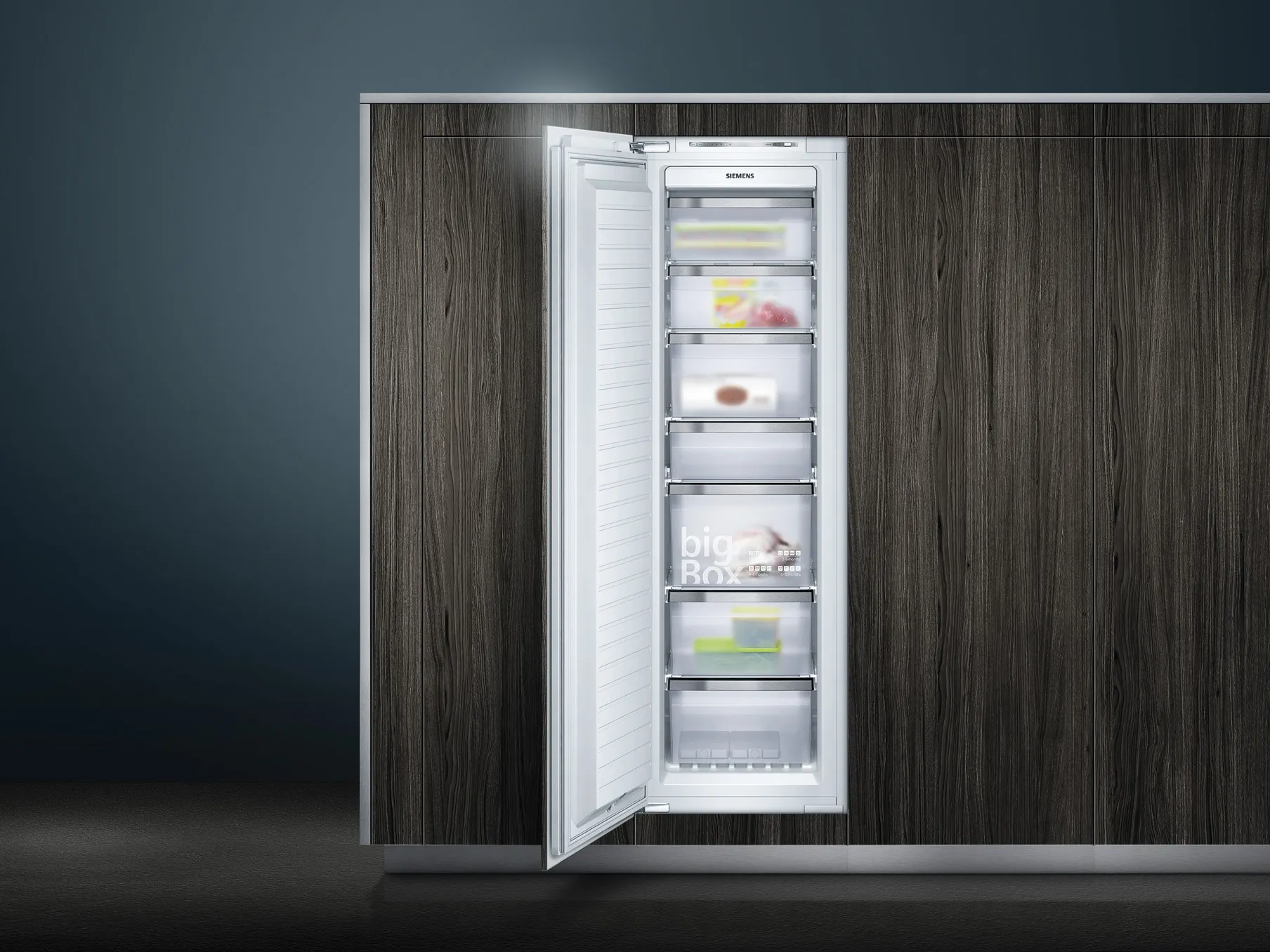 Built-in upright freezer with the door open, revealing seven clear pull-out drawers containing assorted frozen items.
