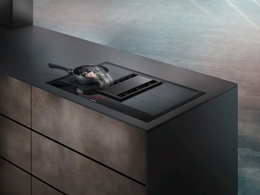 Black kitchen cabinet with induction cooktop and cooking pot.