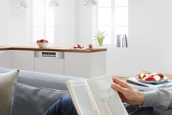 &nbsp;Eine Person liest ruhig auf dem Sofa, w&auml;hrend ein Bosch Geschirrsp&uuml;ler in der N&auml;he l&auml;uft.&nbsp;