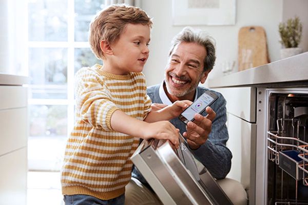 Man shows his grandson his dishwasher with Home Connect.
