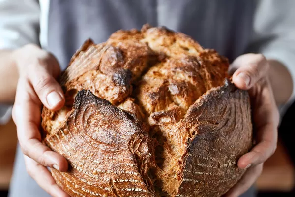 Deux mains portant du pain fait maison