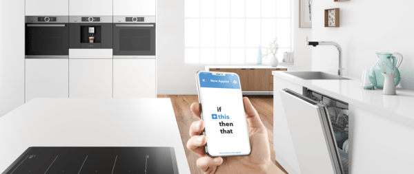 Hand i kök håller mobiltelefon med IFTTT-app