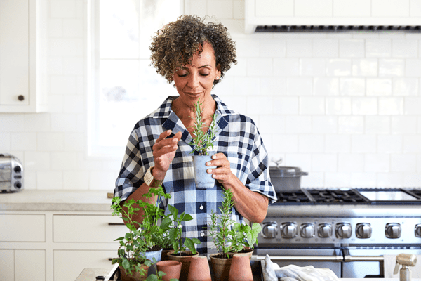 Beeld bij artikel over binnenshuis tuinieren: een vrouw die planten verzorgt