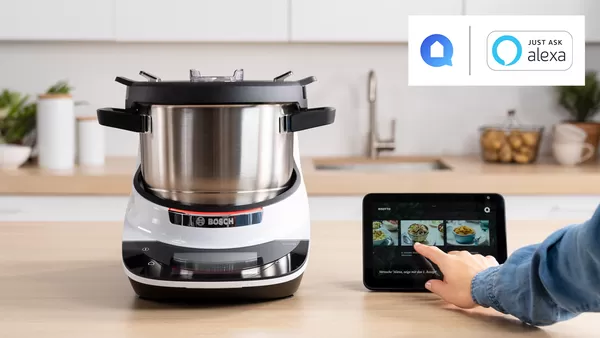 Cookit on a kitchen table with Amazon Echo Show device next to it selecting a new recipe to cook.