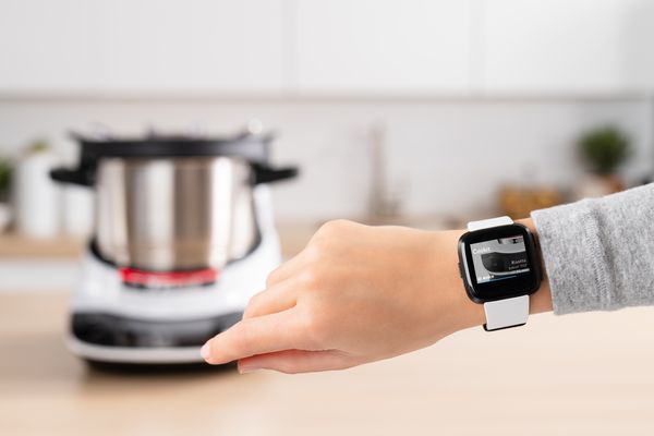 A Fitbit smartwatch on a wrist in front of a Cookit