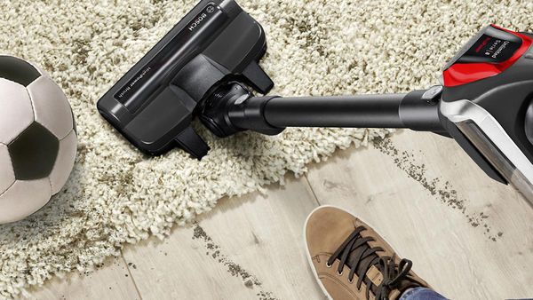 Eine Person saugt einen Teppich mit einem Bosch Unlimited ProPower Akku-Staubsauger.