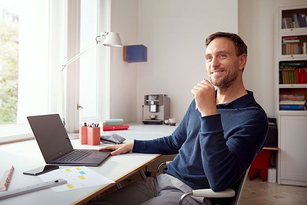 Un homme assis devant un bureau avec un ordinateur portable