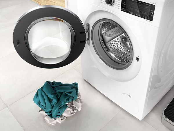Bosch Waschmaschine mit ge&ouml;ffneter T&uuml;r und kleinem W&auml;scheberg davor