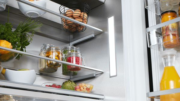 Open stainless steel fridge with side lighting
