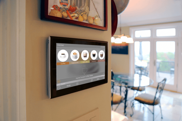 Pannello URC Smart Home con tipi di caffè sul display fissato a una parete, sala da pranzo sullo sfondo