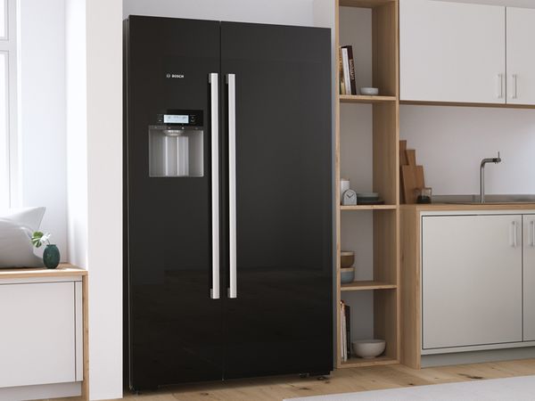 Schwarzer, freistehender Side-by-Side-K&uuml;hlschrank in einer hellen, modernen K&uuml;che.