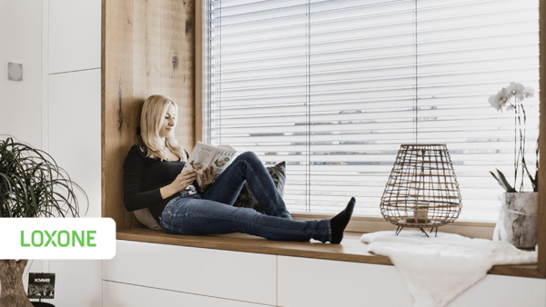 Frau sitzt auf der Fensterbank und liest ein Buch