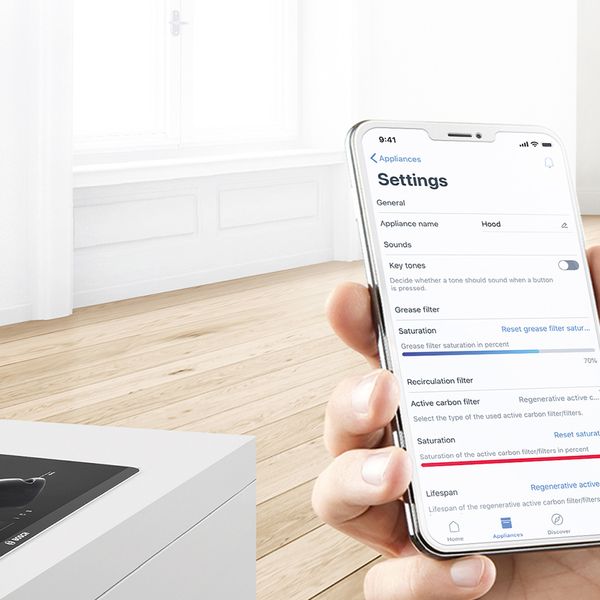 Die Home Connect App auf einem Smartphone. Ein intelligentes Kochfeld mit einer Pfanne im Hintergrund.