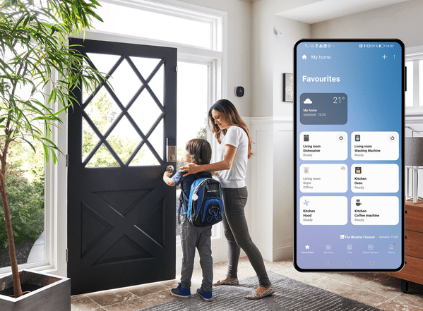 Eine Mutter verlässt mit ihrem Sohn das Haus durch die Eingangstür, Smartphone mit SmartThings App-Oberfläche im Vordergrund