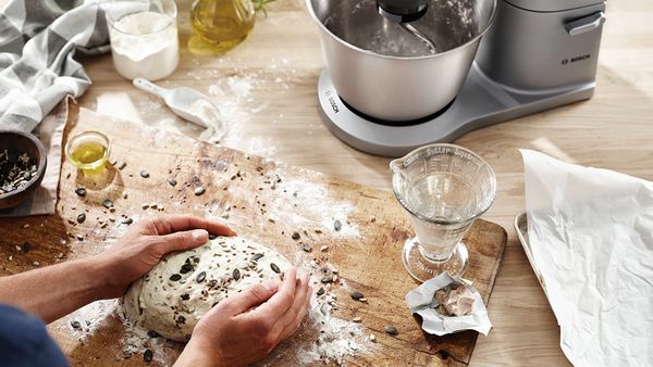 K&uuml;chenmaschine und Frau die Brotteig zubereitet