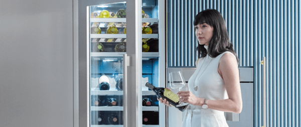 Woman taking out wine bottle from Thermador wine refrigerator to drink