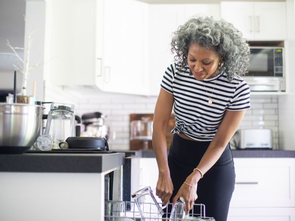 Vrouw haalt schone vaat uit vaatwasser