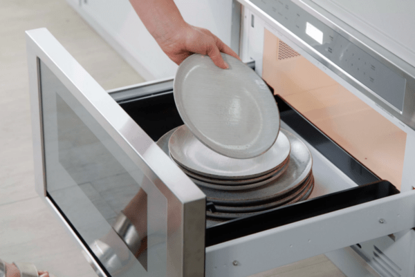 Bras mettant de la vaisselle dans le lave-vaisselle