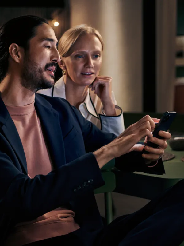 Two people, a man and a woman, sitting together and looking at a mobile device.