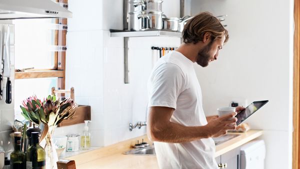 Man looking at tablet for connected devices in kitchen 