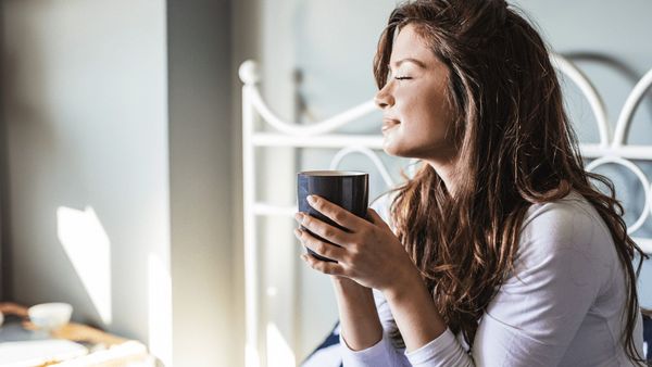 Woman sitting in bed with a cup of coffee