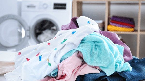 Pile of clothing in front of open washing machine