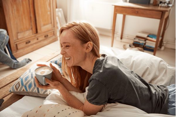 Woman with coffee on bed